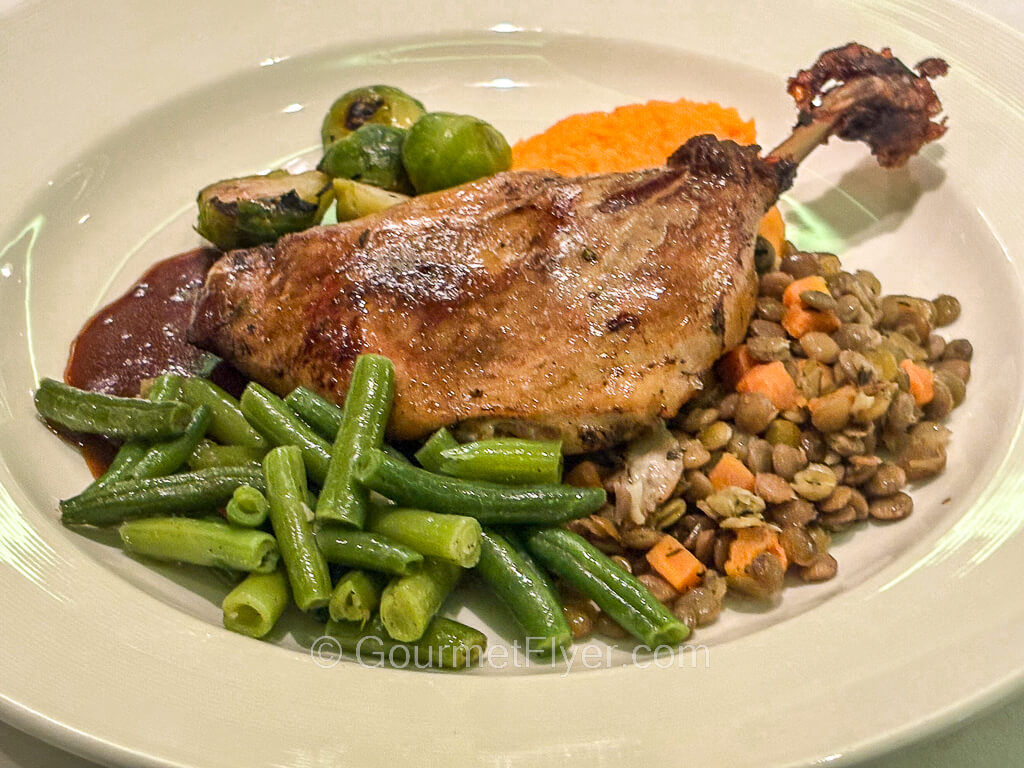 A duck leg and thigh is served with green beans and lentil salad.