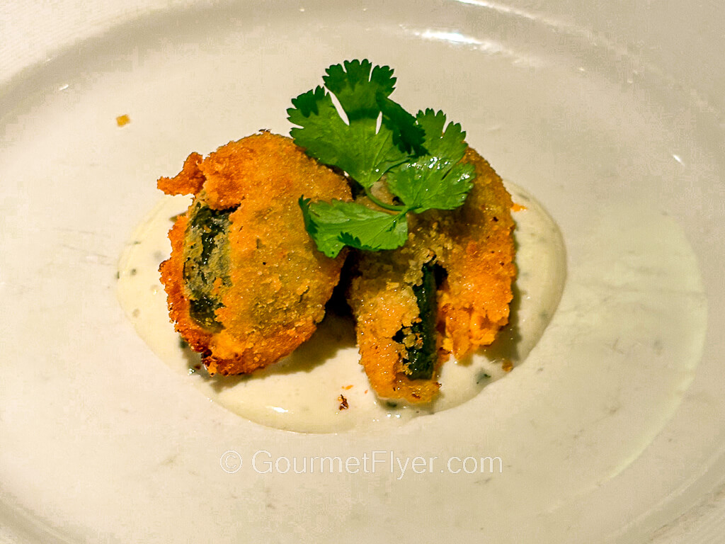 Two pieces of golden-brown fried vegetables are garnished with mint leaves.
