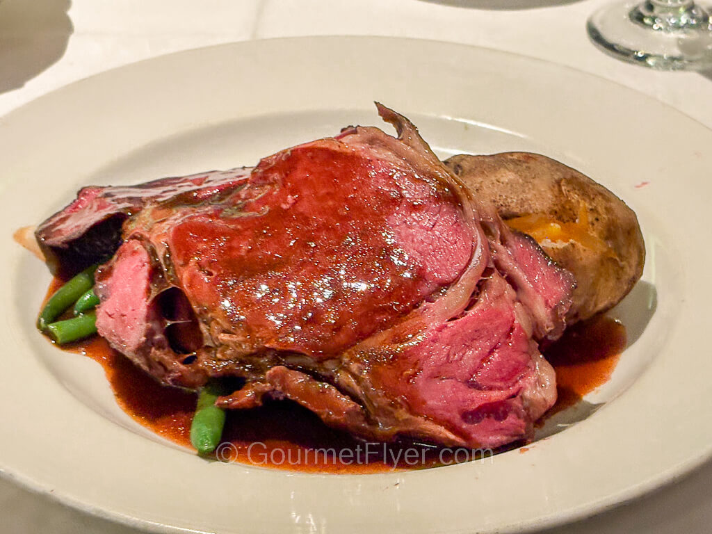 A rare cut of roast beef is covered in a pool of brown gravy.
