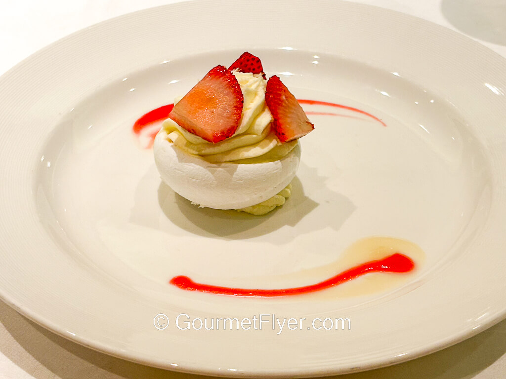A strawberry dessert is topped with whipped cream.