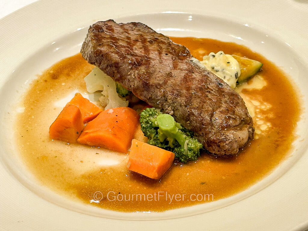 A grilled steak is served with mashed potatoes and mixed vegetables.