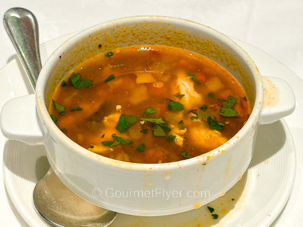 A bowl of tomato based soup with vegetables.