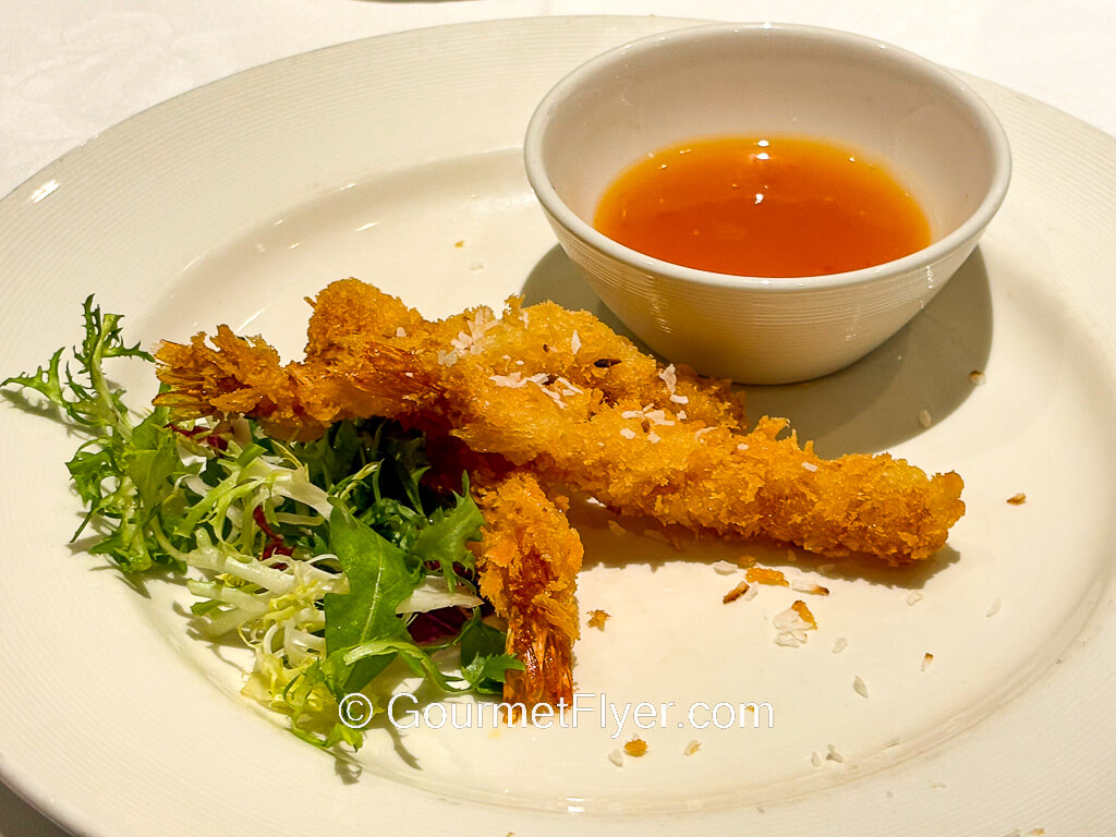 Fried shrimps are served with a side of reddish color dipping sauce.