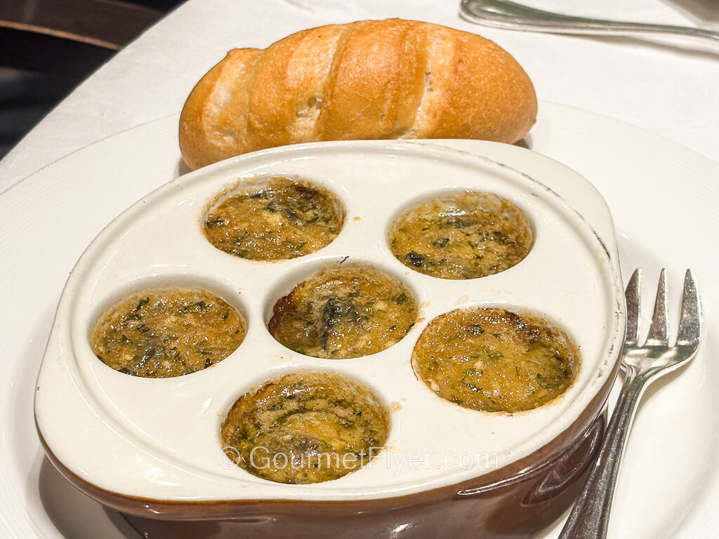 Escargots are served in a 6-holed compartmented dish.