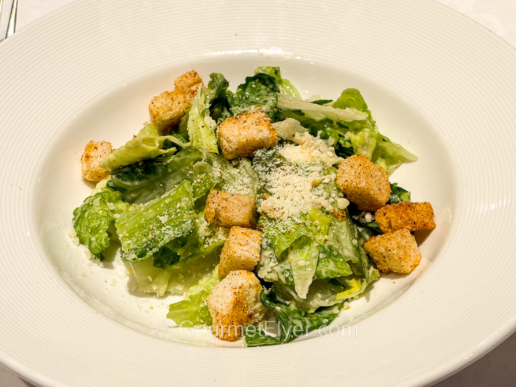 A green salad is topped with grated cheese and croutons.