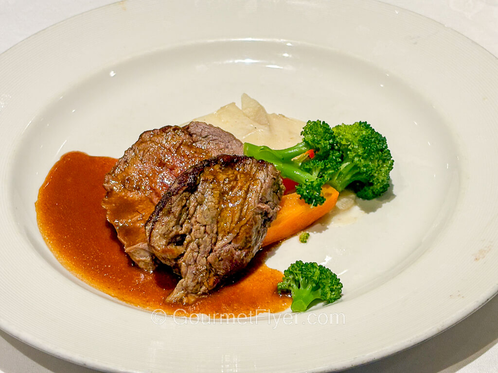 Slices of beef are accompanied by a brown gravy and broccoli florets.