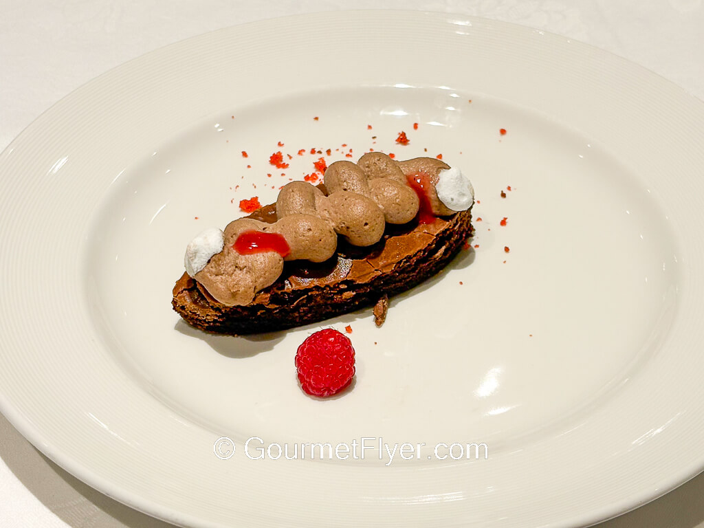 A chocolate dessert is accompanied by raspberries.