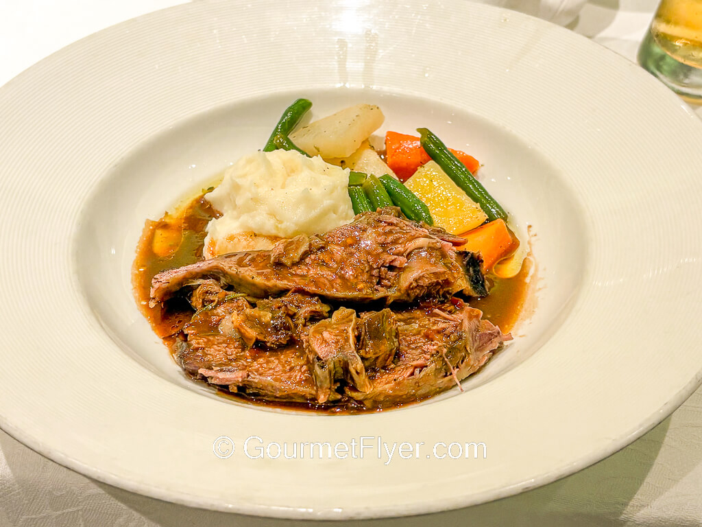 Beef stews are served with mashed potatoes and veggies in a bowl.