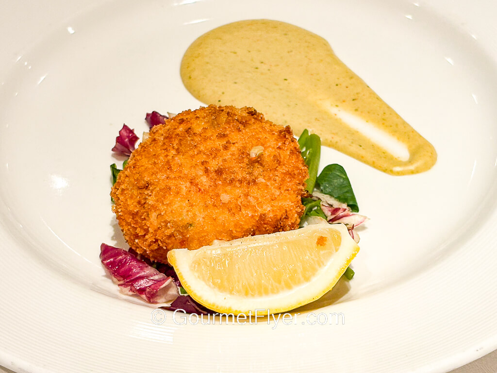 A fried dumpling is served with a yellow mustard sauce.