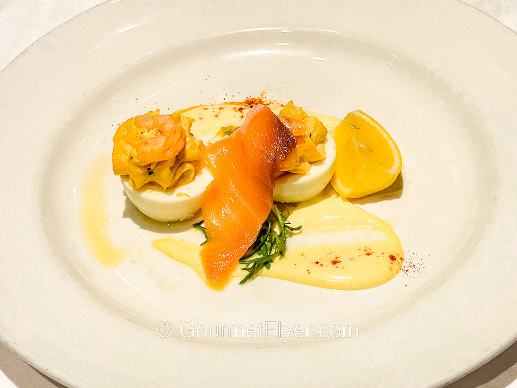 A pair of deviled eggs are paired with a sliced of salmon.