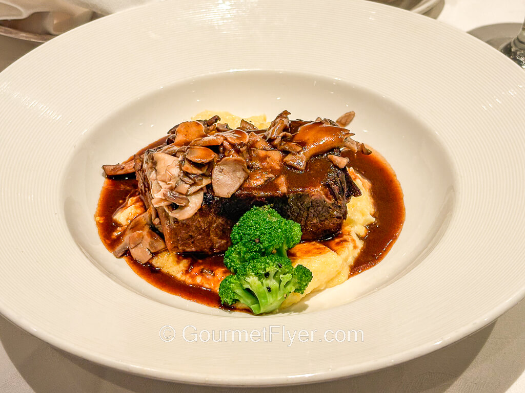 A slab of beef is served over mashed potatoes and a pool of brown gravy.