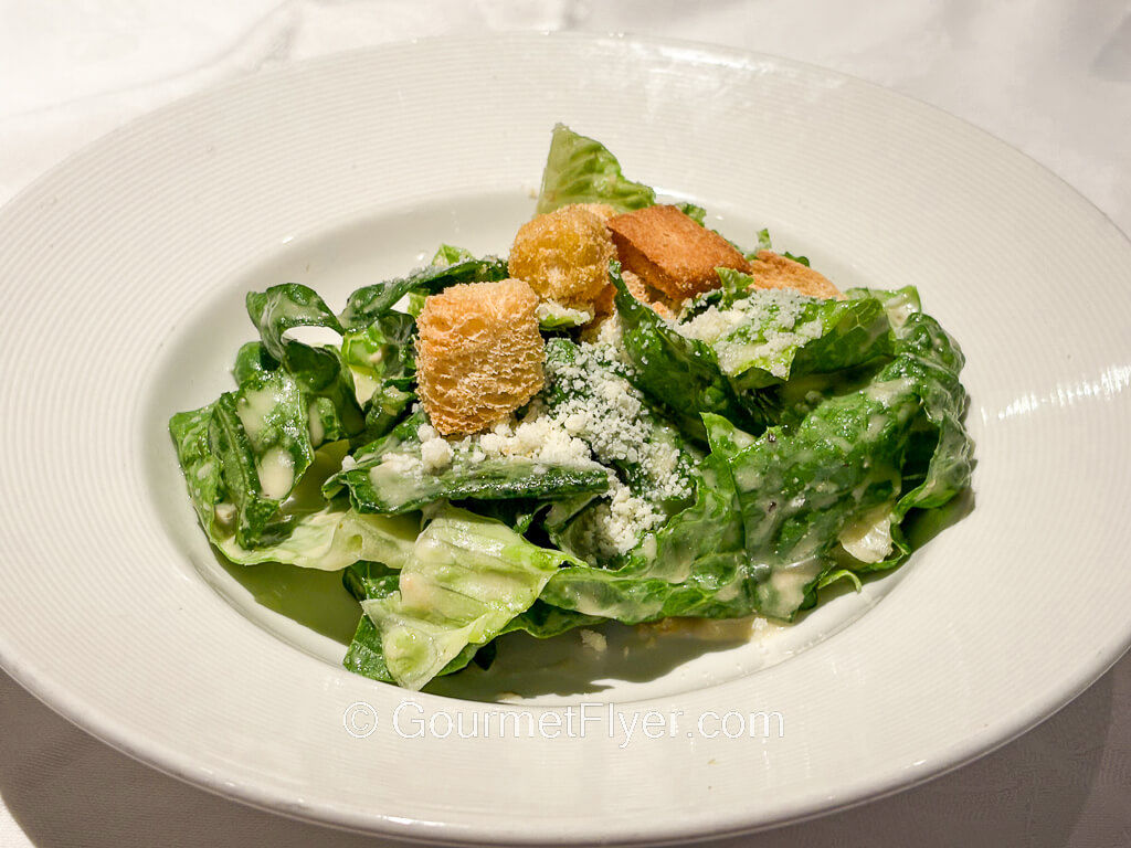 A green salad is topped with grated cheese and croutons.