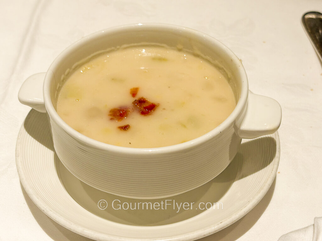 A bowl of white creamy soup garnished with red peppers.