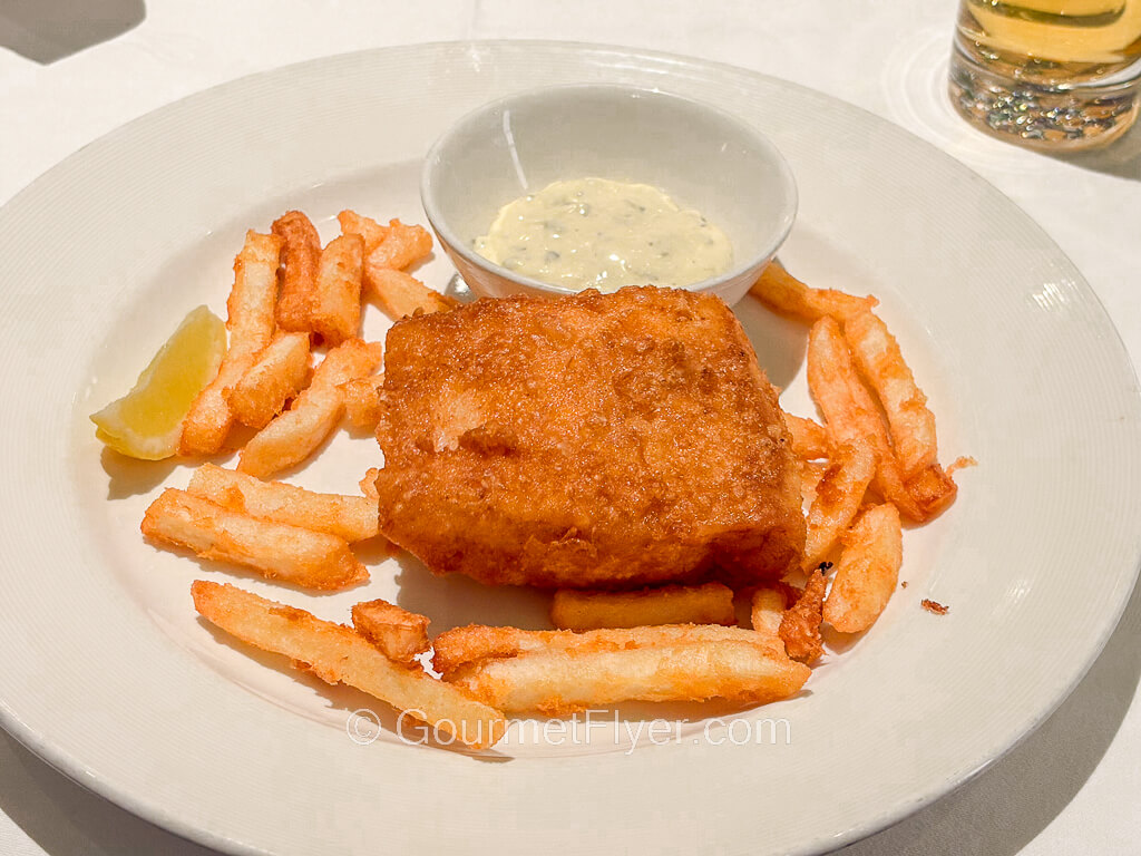 A square piece of fried fish is accompanied by French fries.