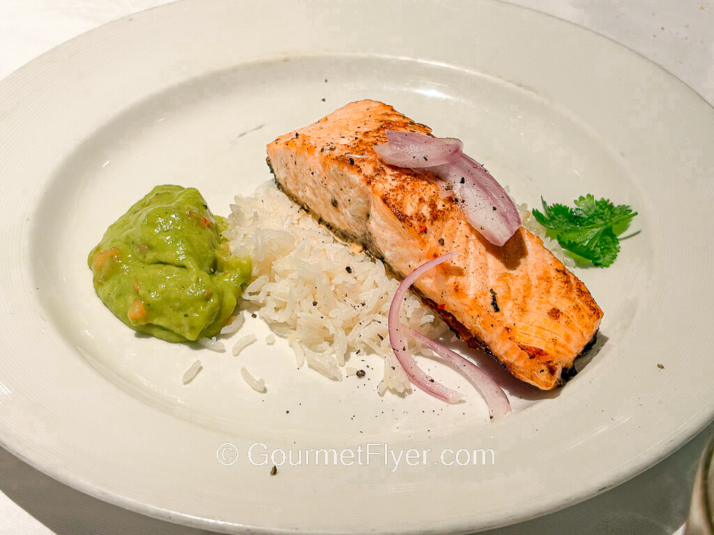 A salmon filet is served with white rice on a plate.