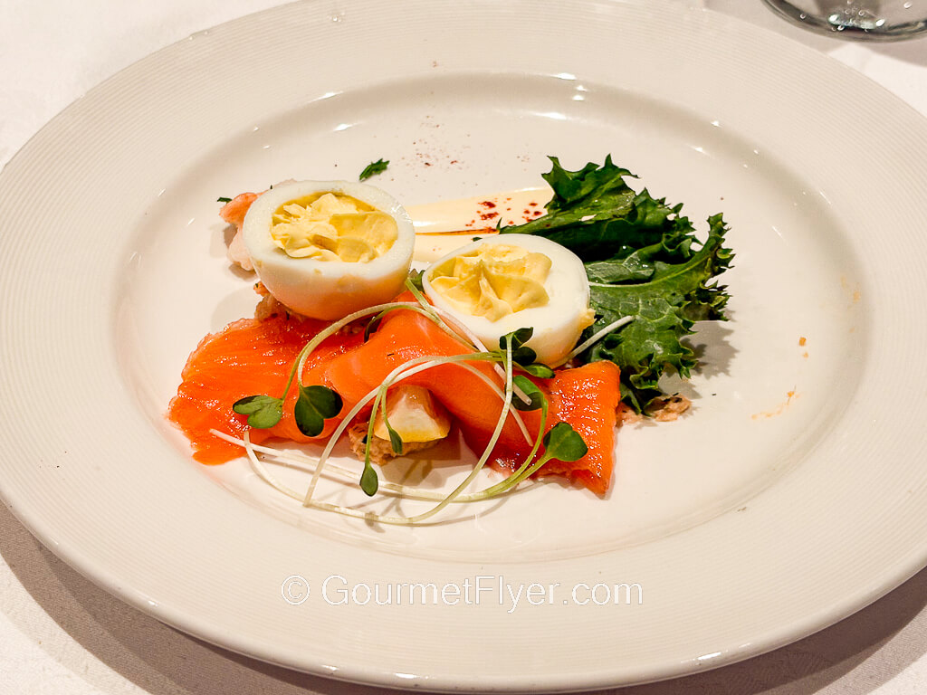 A slice of salmon is accompanied by a pair of deviled eggs.