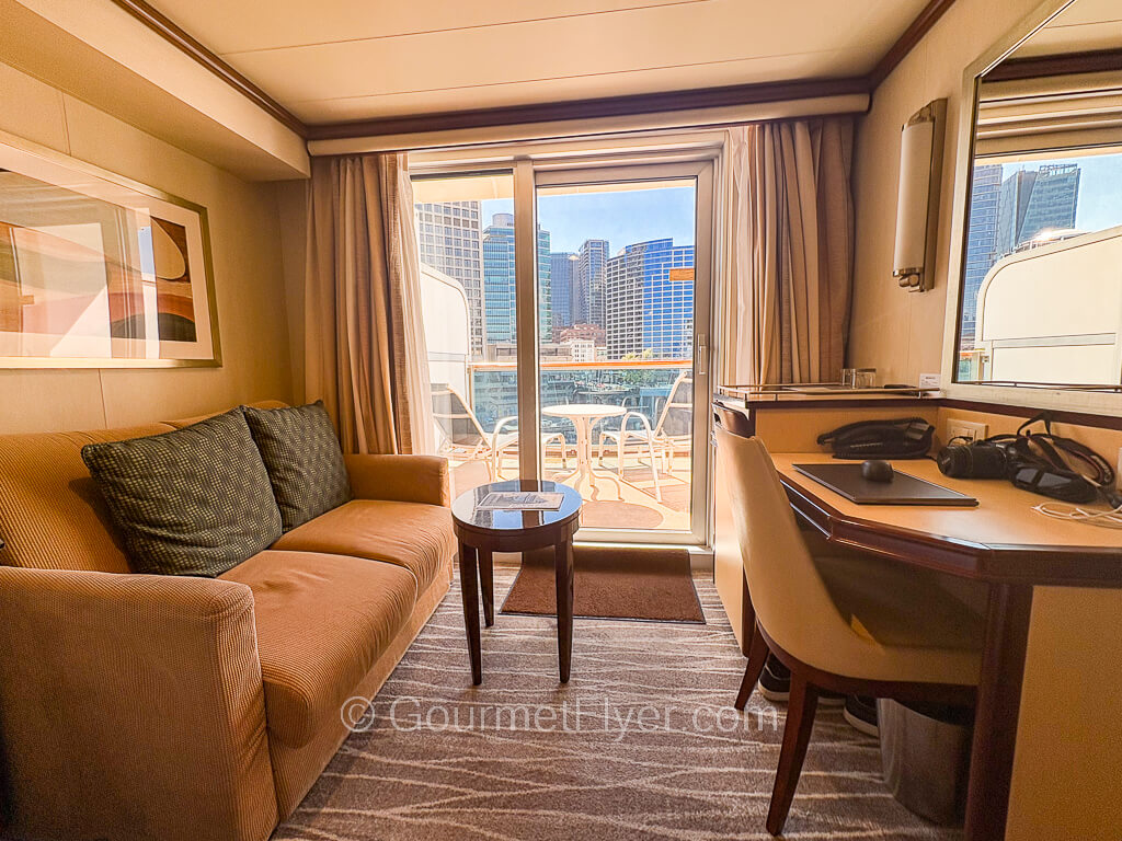 A sofa and a desk are shown in front of a sliding glass door leading to the balcony.