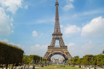 A 3-day in Paris itinerary features the Eiffel Tower standing behind a green landscape under a sunny blue sky.
