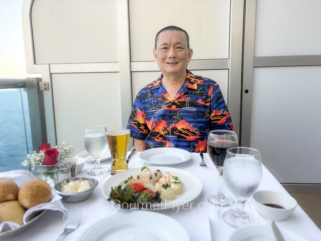 Princess Cruises Ultimate Balcony Dining Menu and Review features a blogger sitting in front of a table with white tablecloth and a full setting of tableware.