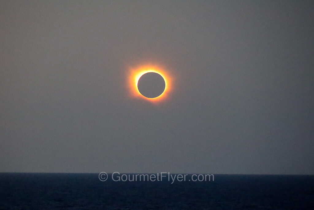 A total solar eclipse viewing on the Enchanted Princess cruise features the bright orange corona on the outer rim of the moon.