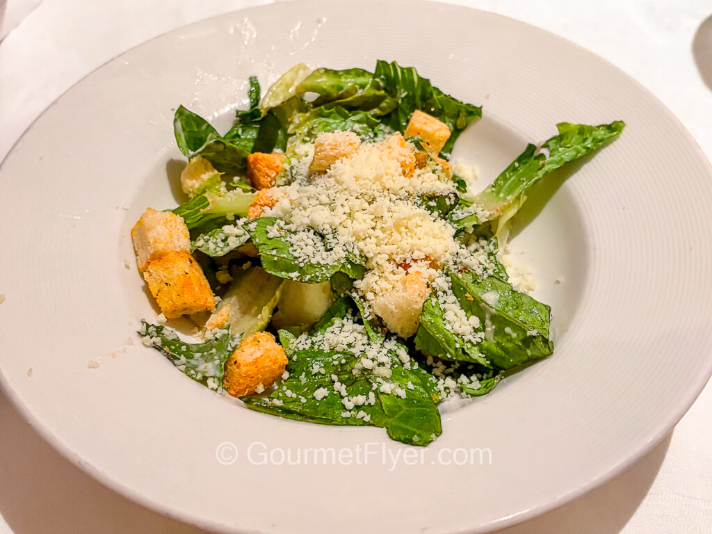A green leafy salad is topped with grated cheese and croutons.