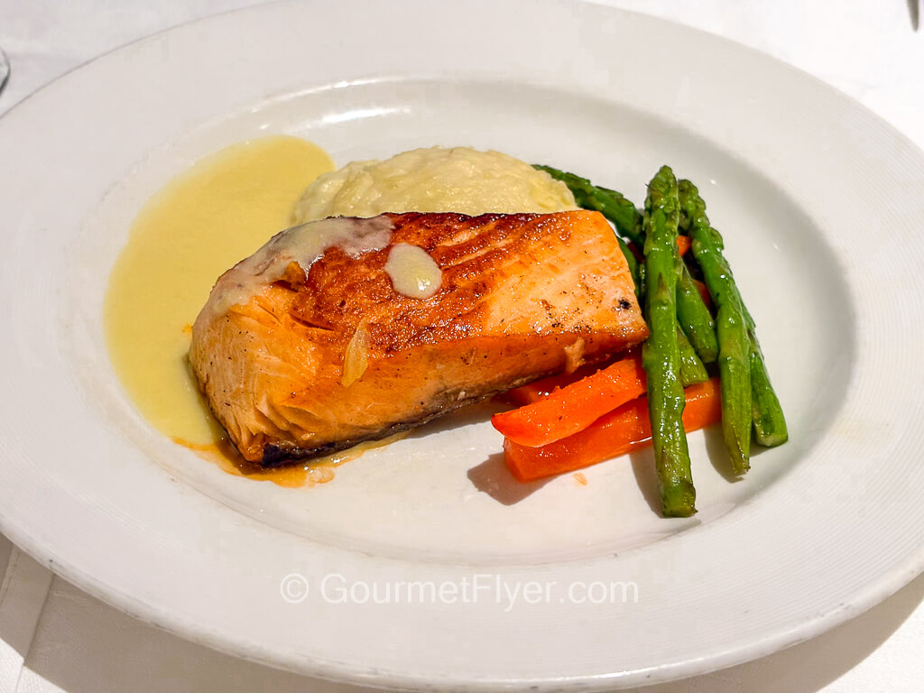 A piece of grilled fish is served with asparagus spears.