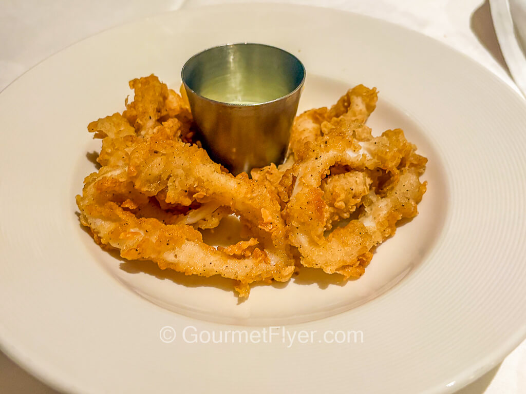 Several pieces of golden-brown fried food is served with sauce on the side.