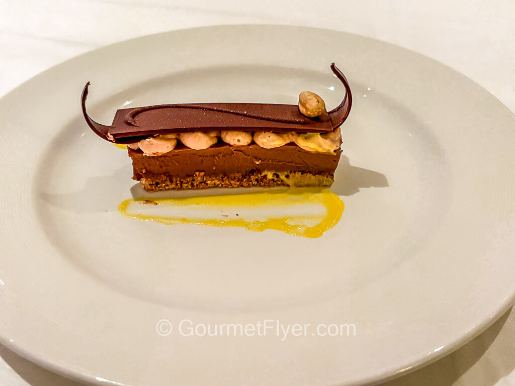 A slice of chocolate cake is garnished with a twirl of yellow syrup.