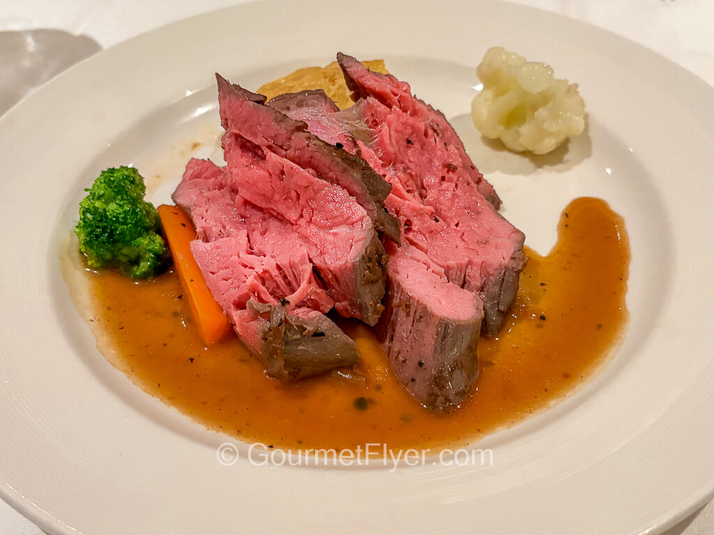 Two thick pieces of rare red meat is served with brown gravy and vegetables.