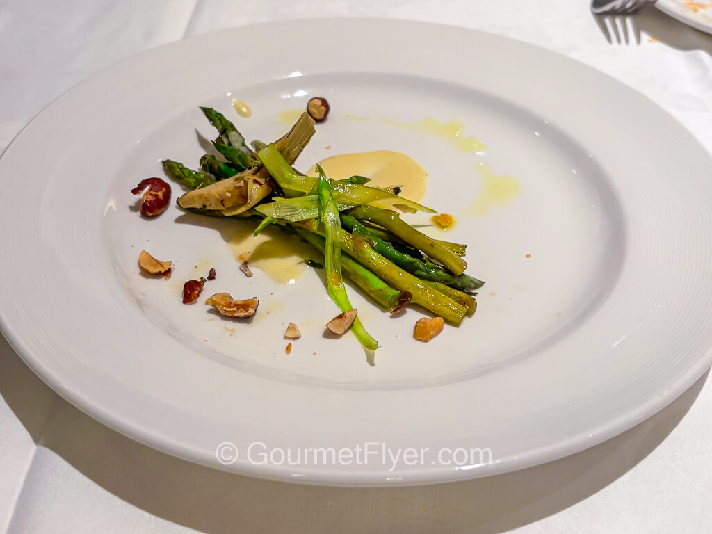 Several asparagus spears are served on a dish with a cheesy cream sauce.