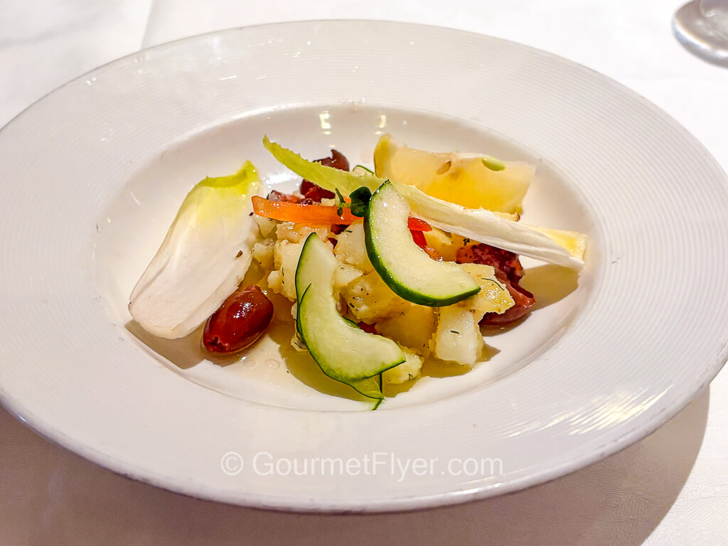 A blended seafood salad includes cucumber, kidney beans, lettuce, and a lemon wedge.