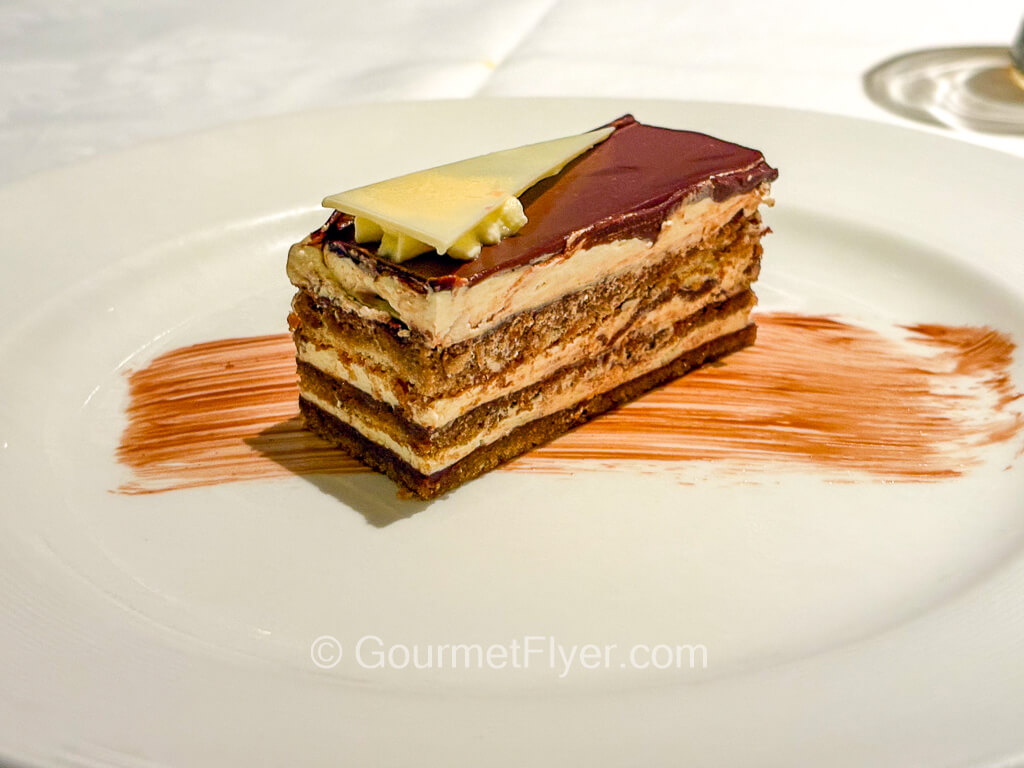 A layered chocolate cake is topped with a piece of white chocolate.