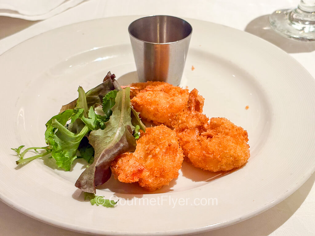 Three pieces of fried shrimps are accompanied by leaves of green lettuce.