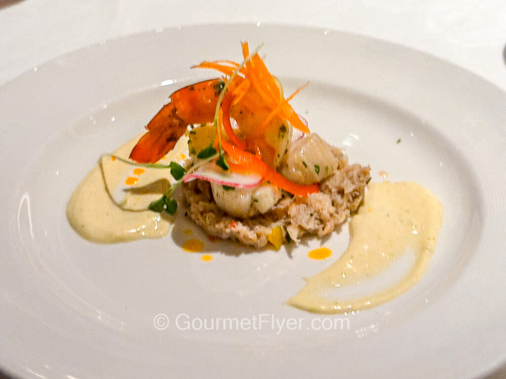 A shelled shrimp is served with scallop and a creamy white sauce.