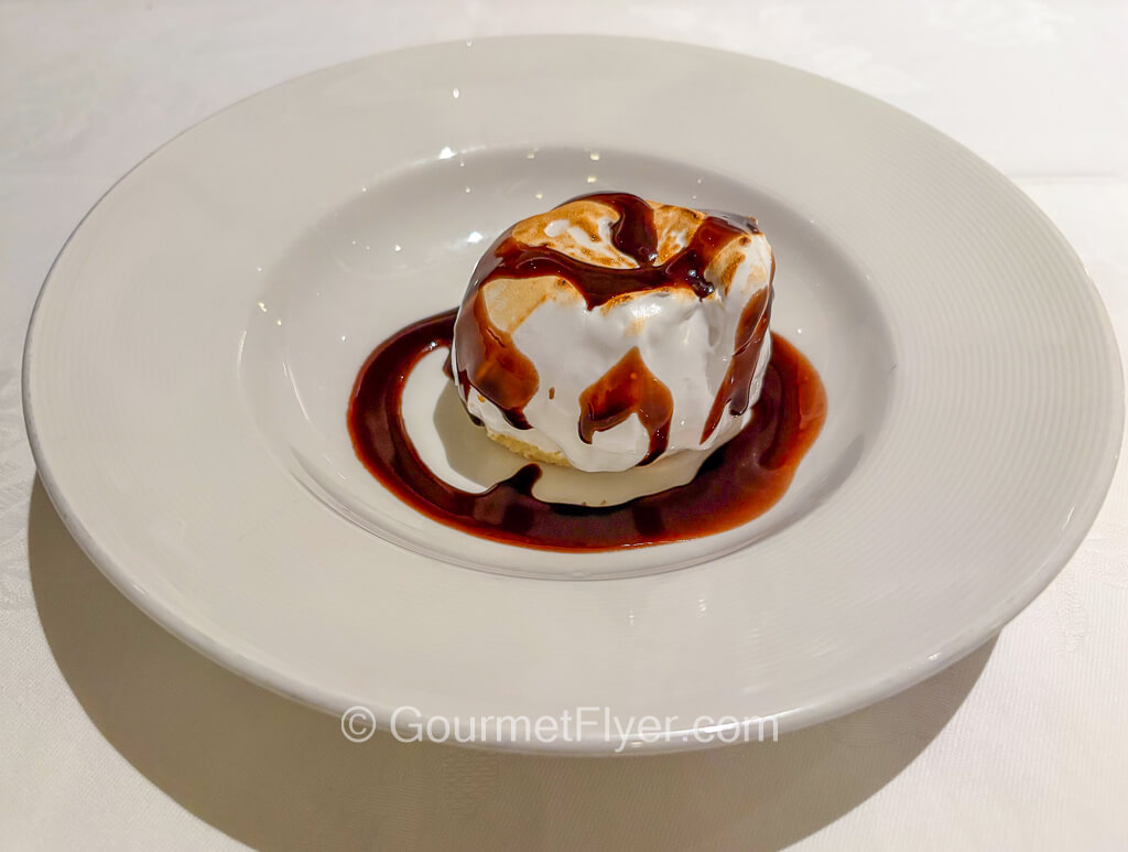 A dessert is drenched in chocolate syrup and covered in whipped cream.