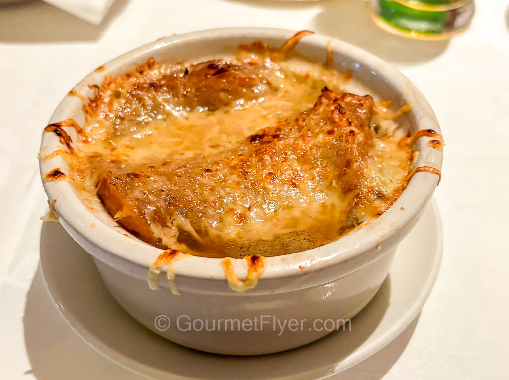 A bowl of baked soup with burnt cheese on top.
